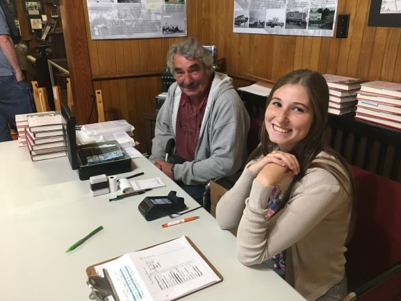 Museum volunteer and summer student smile while selling books